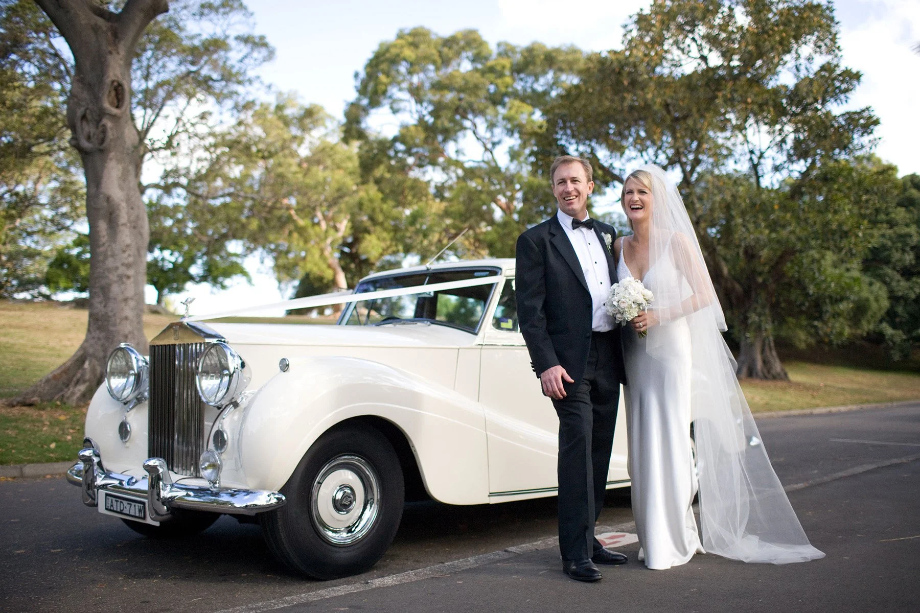 Bride and groom standing beside a classic white Rolls Royce at the Royal Botanic Gardens Sydney