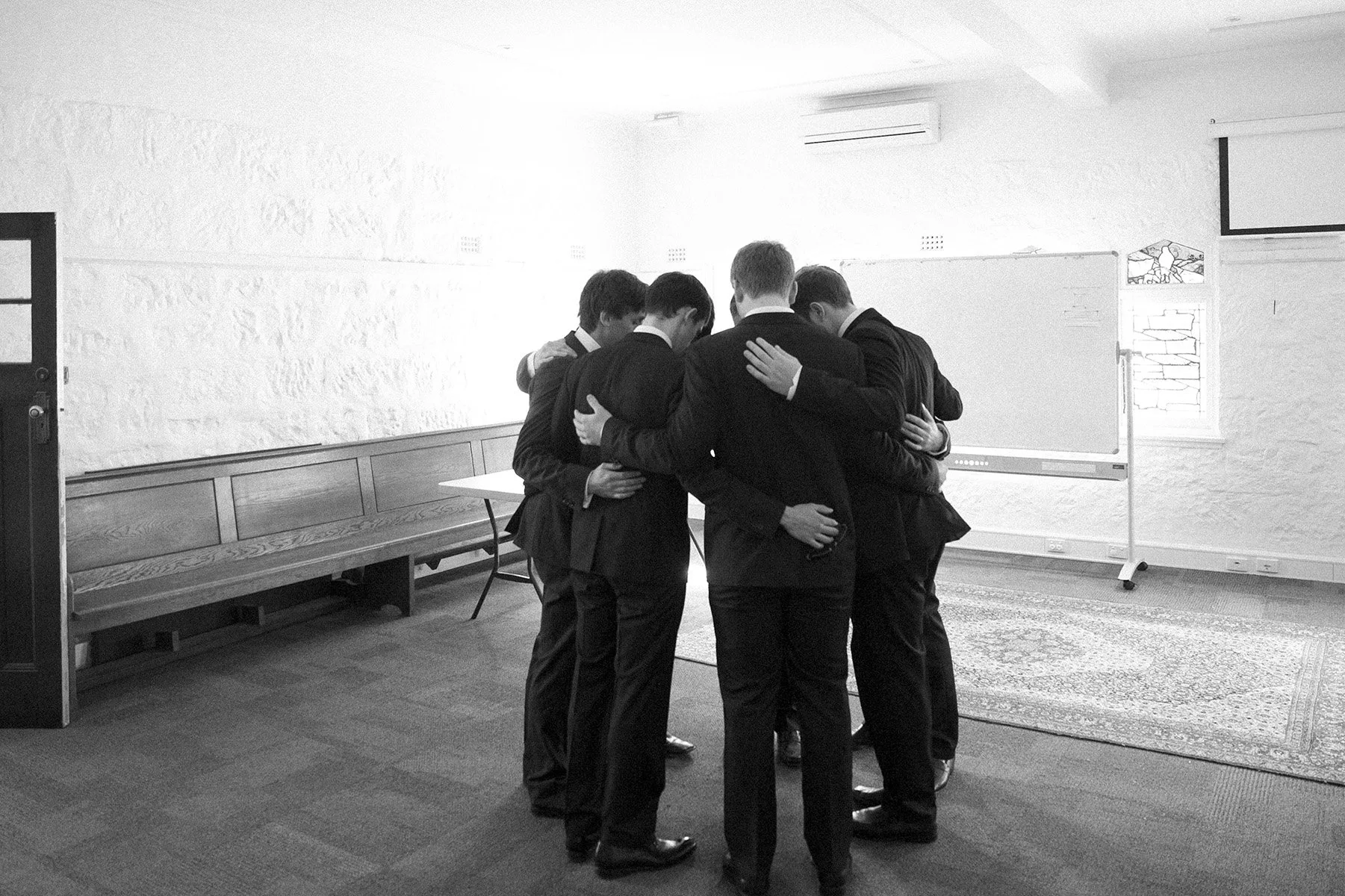 Groom and groomsmen in a huddle praying together before the ceremony, St Andrews Anglican Church Roseville