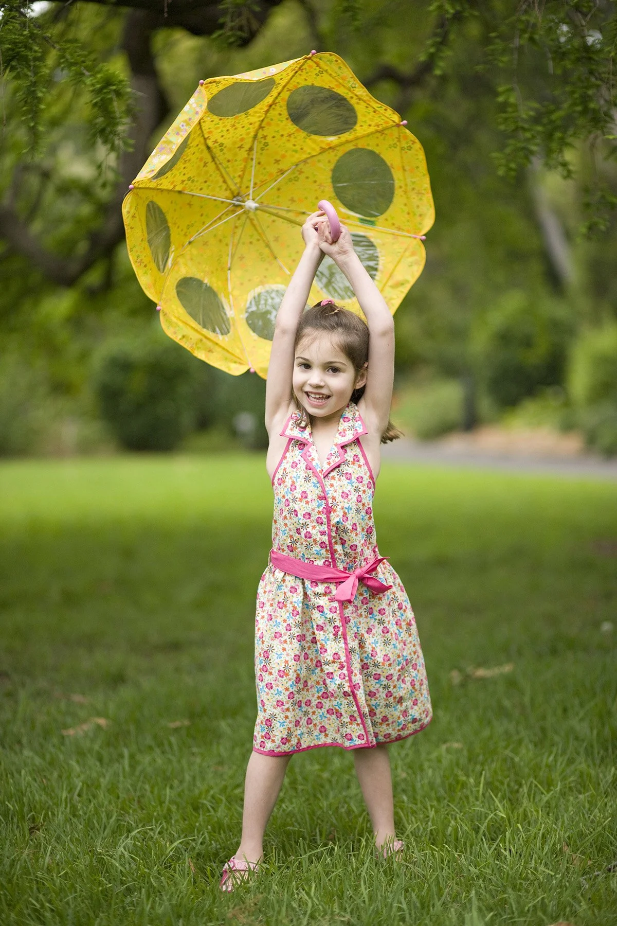 young girl playing with a yellow umbrella in the park
