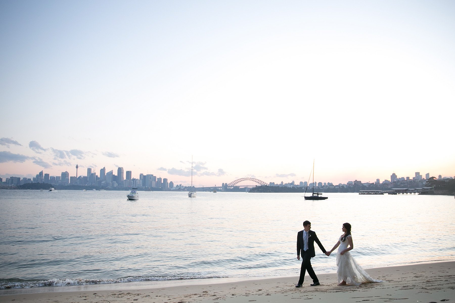 Bride and groom walking hand in hand on Athol beach, Mosman at golden hour