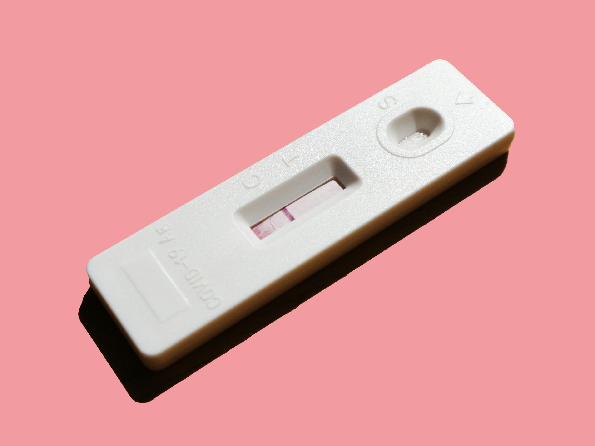A white rapid pregnancy test kit with a pink background, showing a single visible line across the test window.