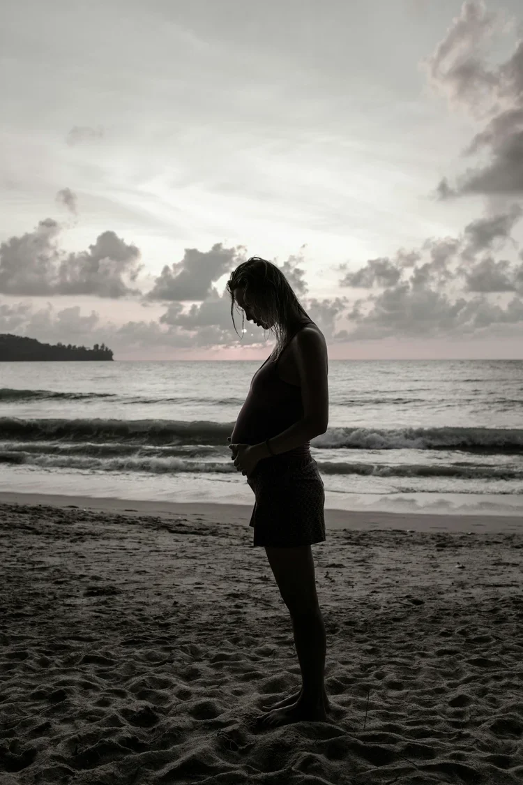 pregnant woman standing on beach