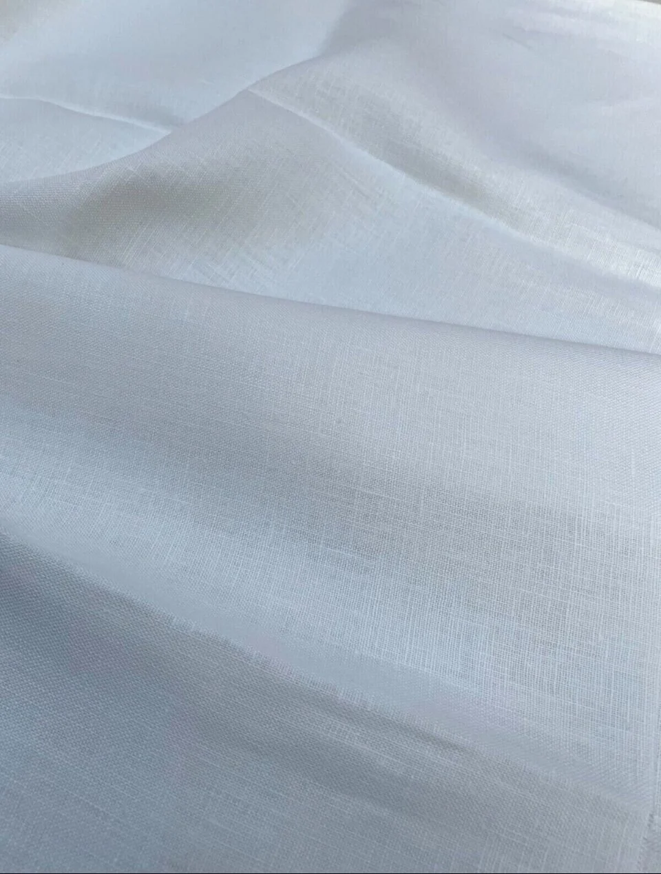 Close-up of white fabric with a subtle woven texture and gentle folds.