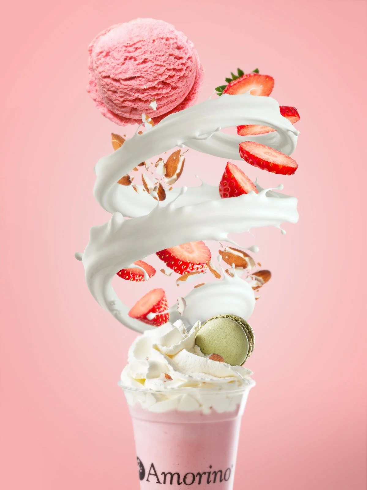 Amorino ice cream milshake cup with whipped cream, strawberries, and macaron on a pink background.