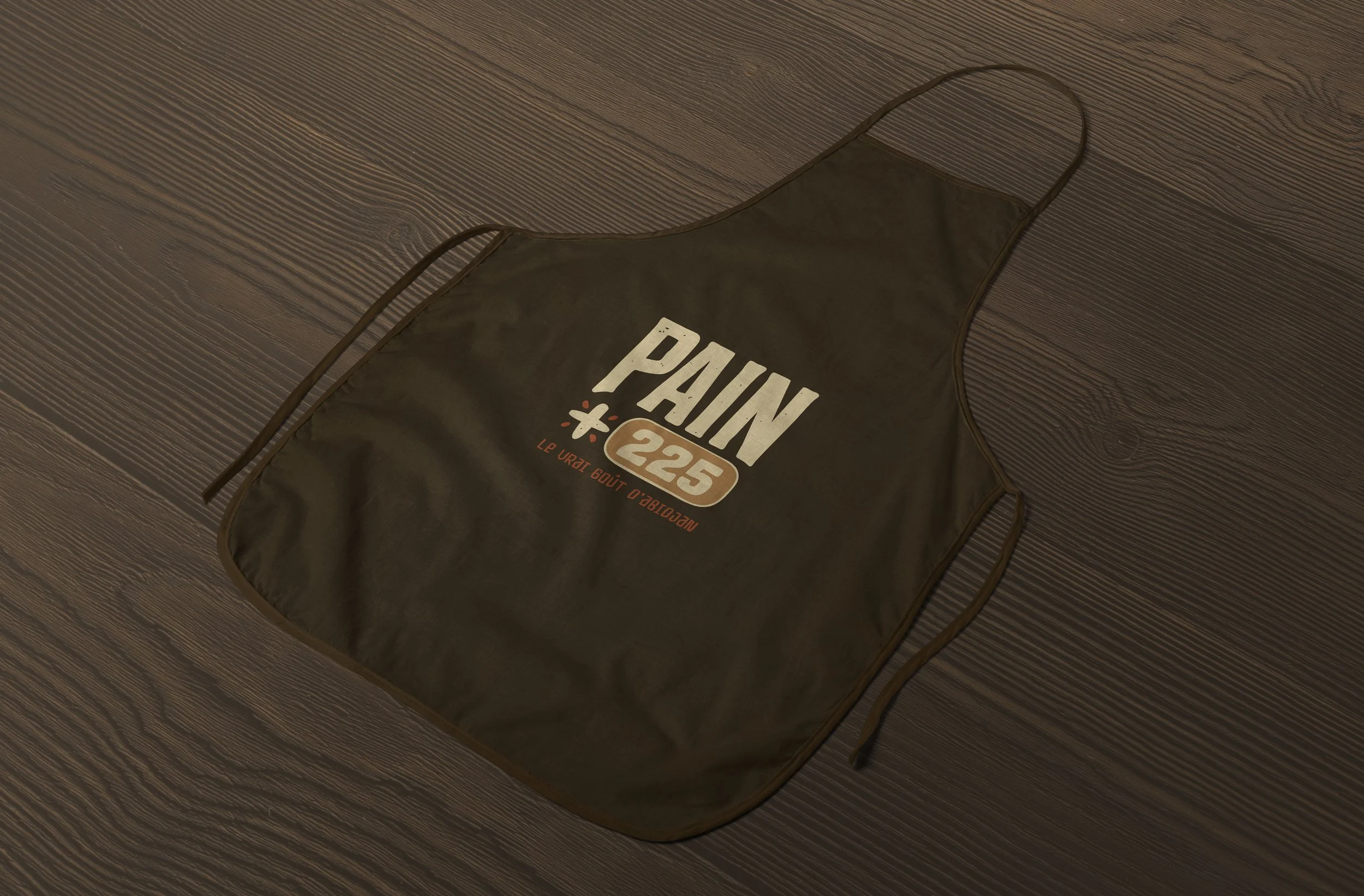 PAIN 225 branded apron laid on a wooden surface.