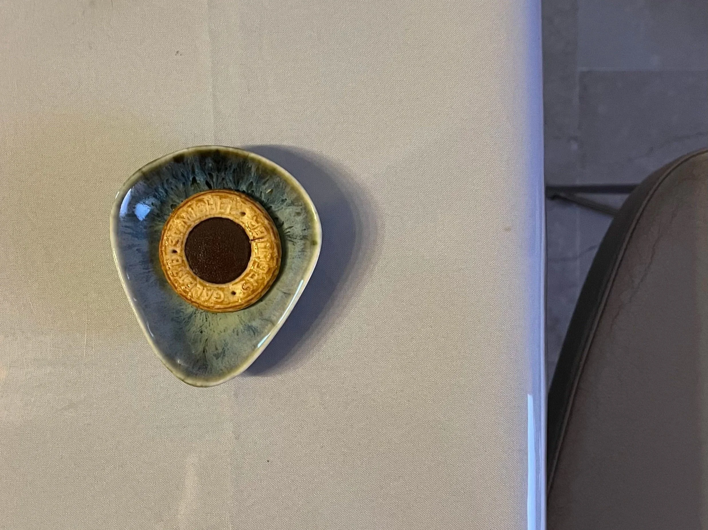 A ceramic dish shaped like an eye with a gold-colored ring in the center, placed on a white table.