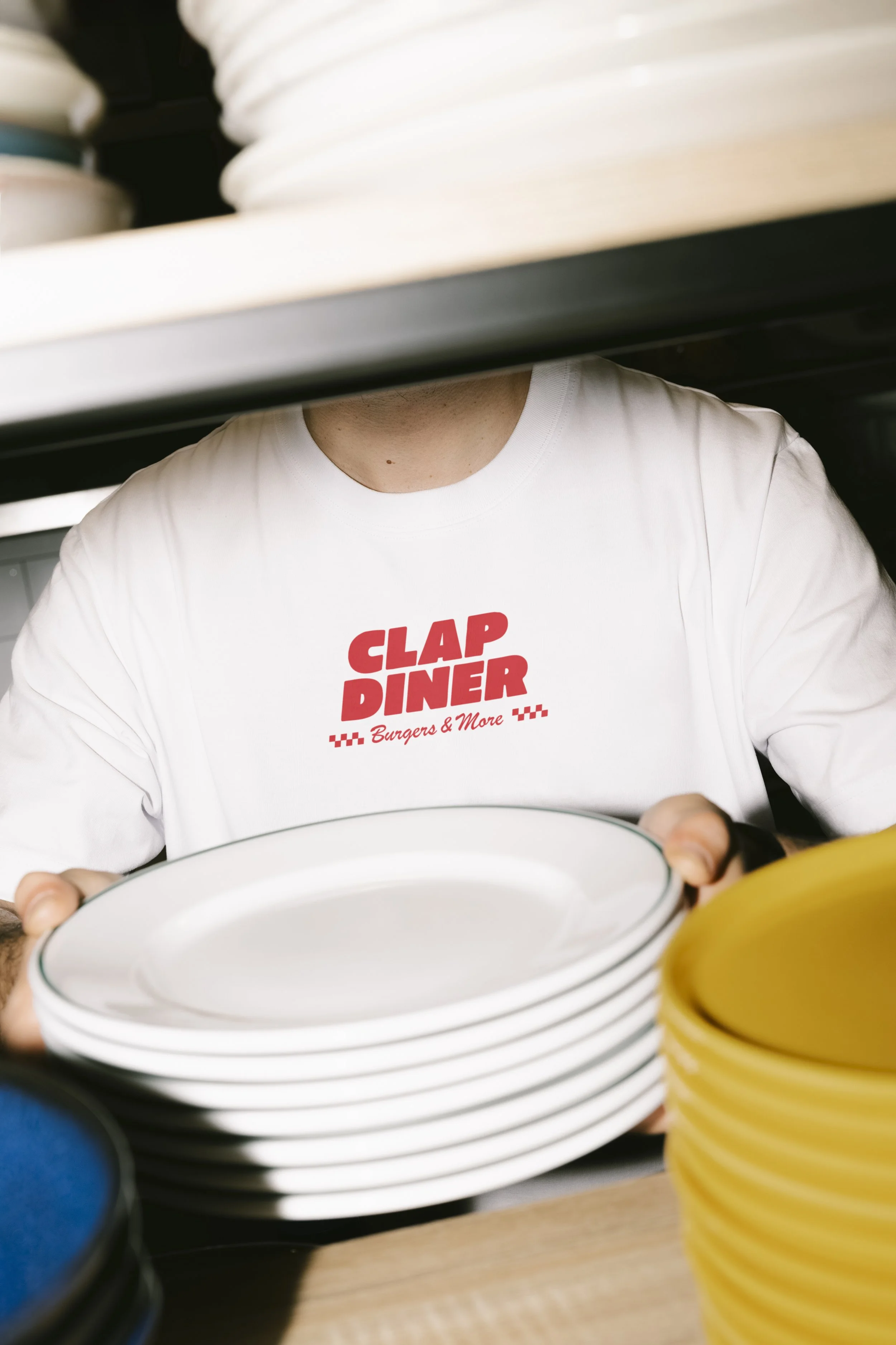 Staff member organizing plates behind the counter at CLAP burger Diner.