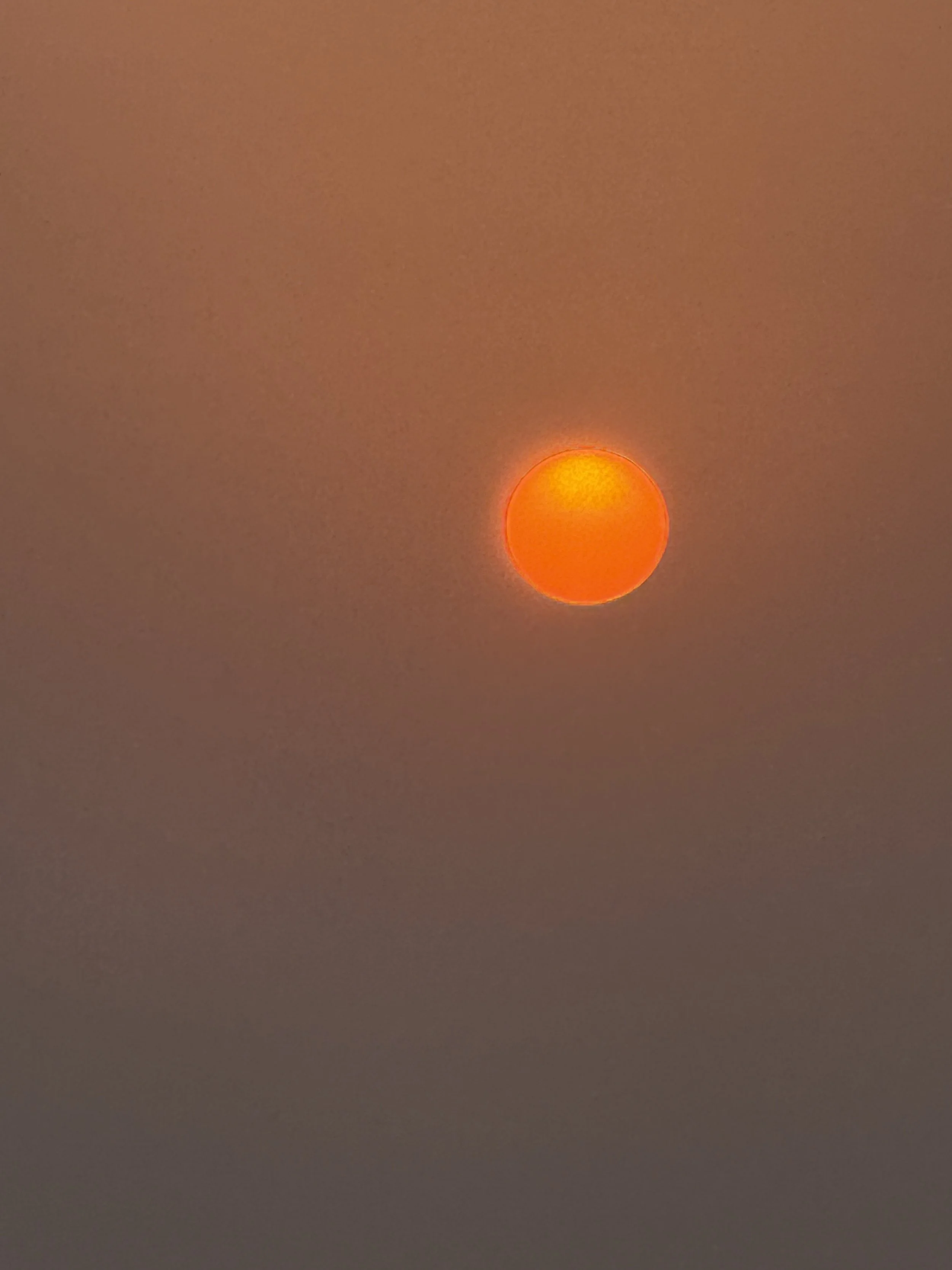 Hazy sunset photograph with an orange sun.