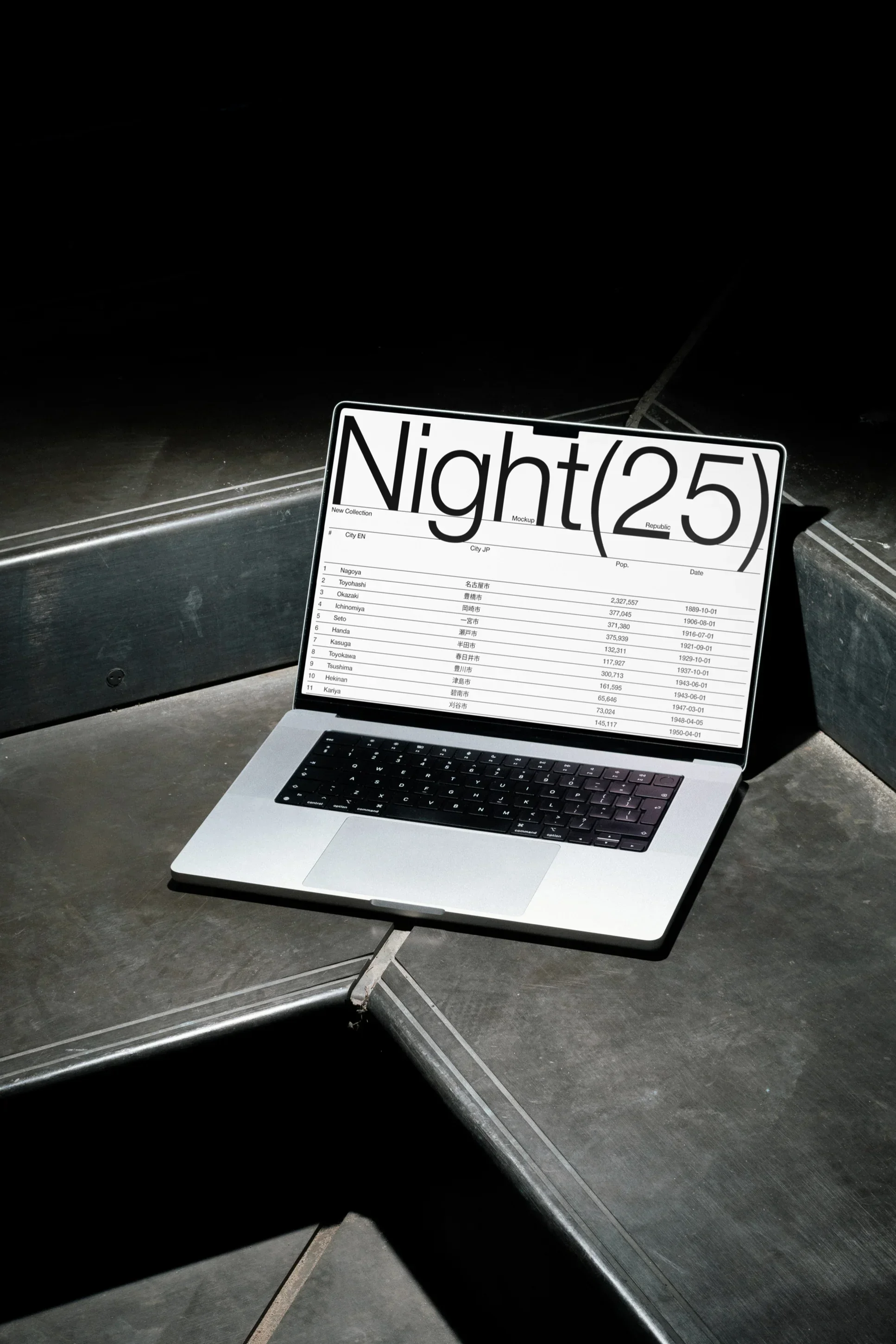 En åpen bærbar datamaskin med en skjerm som viser en liste over byer og datoer, plassert på en mørk betongoverflate i mørket.