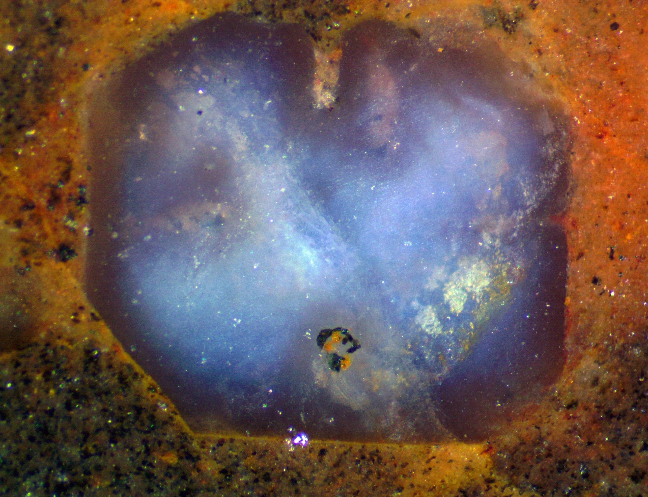 Polished section of the Llano rhyolite (Texas, USA) showing a blue quartz grain with a color zoning shaped by the magmatic corrosion gulfs, and chatoyancy,