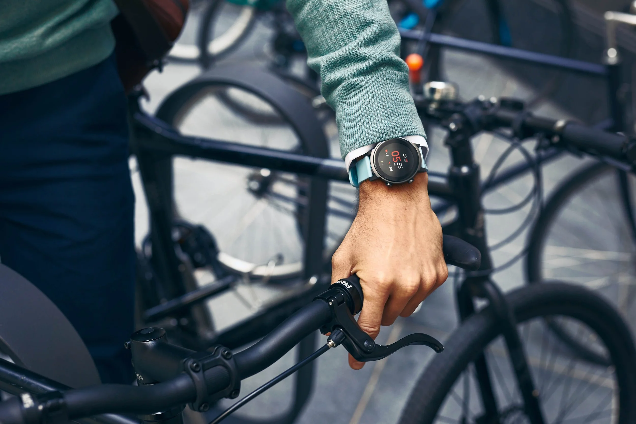 A mans hand, wearing a smartwatch, pushed his bike in the city in this lifestyle photography for Mobvoi by Jon Enoch.