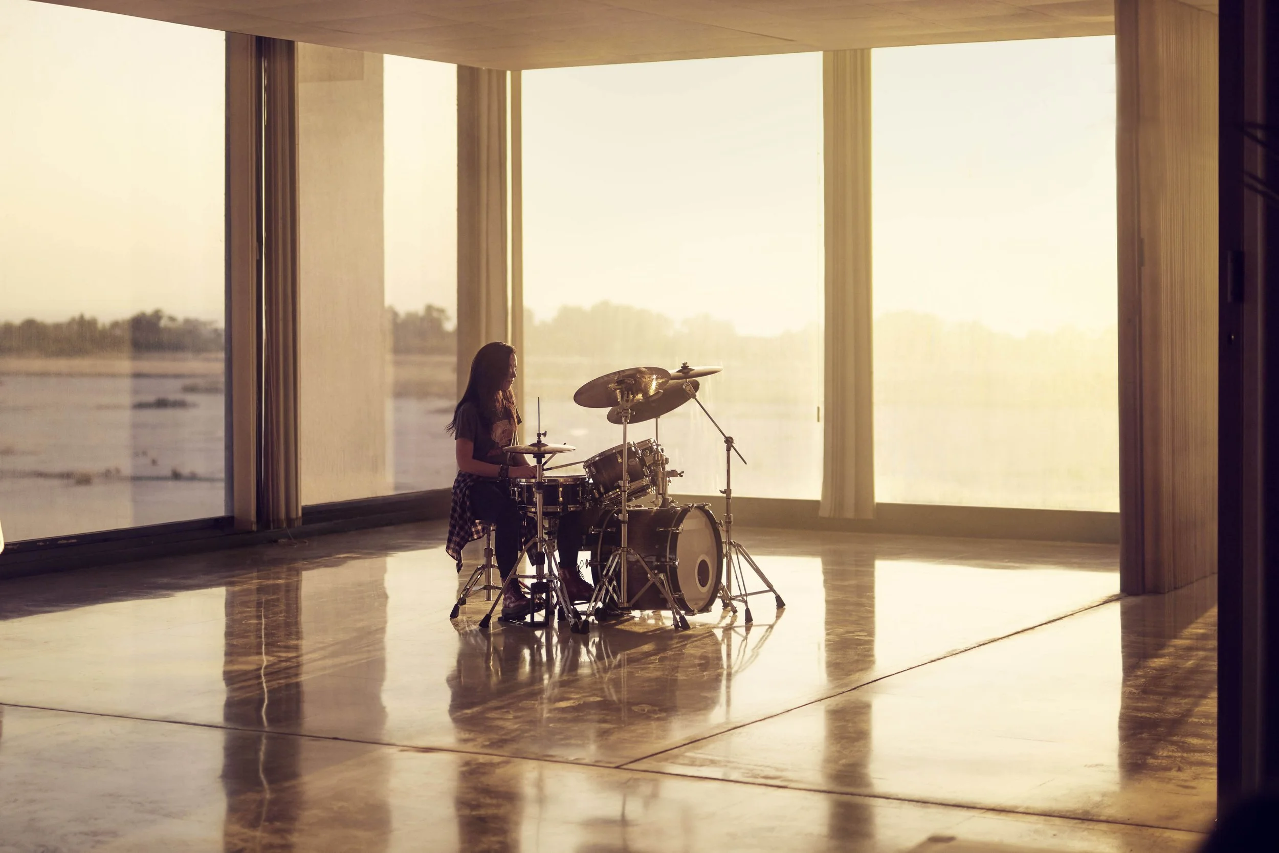 A drummer sits at her drum set in the lifestyle image from photographer Jon Enoch