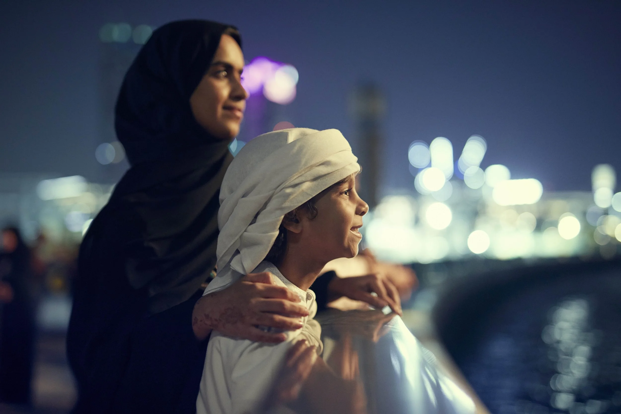 A mother and her son looks out at the night skyline of Dubai in this lifestyle advertising image by Jon Enoch