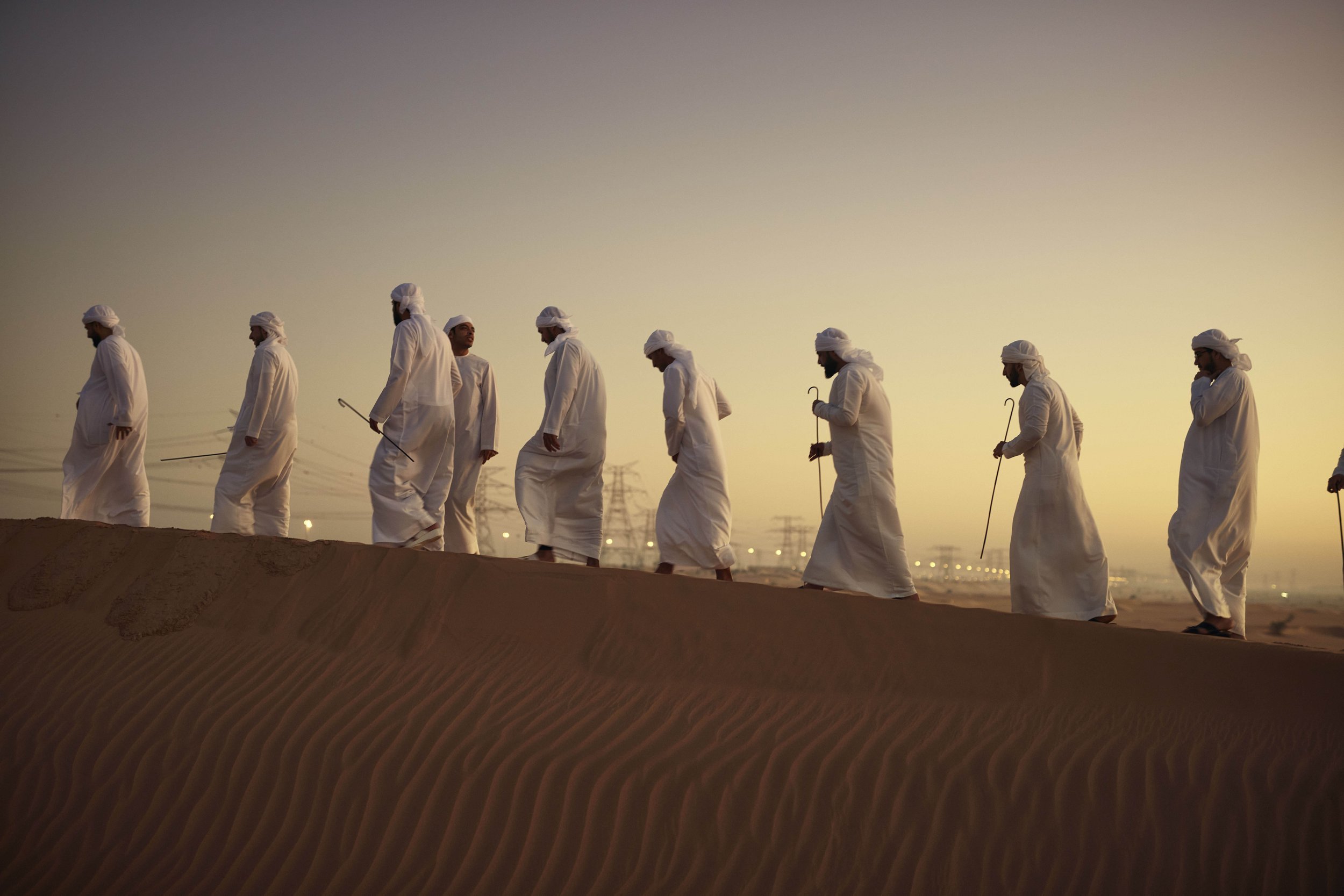 Men in traditional arabic dress walk in the desert at dawn in this advertising photography from Jon Enoch