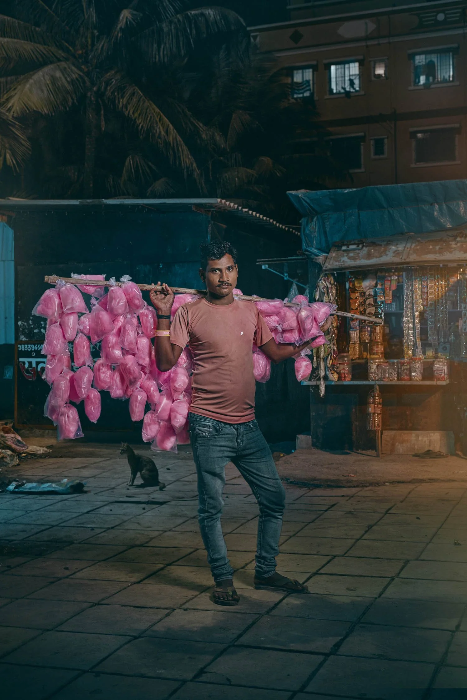 A man holds a display of candy floss that he sells on the streets of Mumbai, India. Portrait by photographer Jon Enoch.