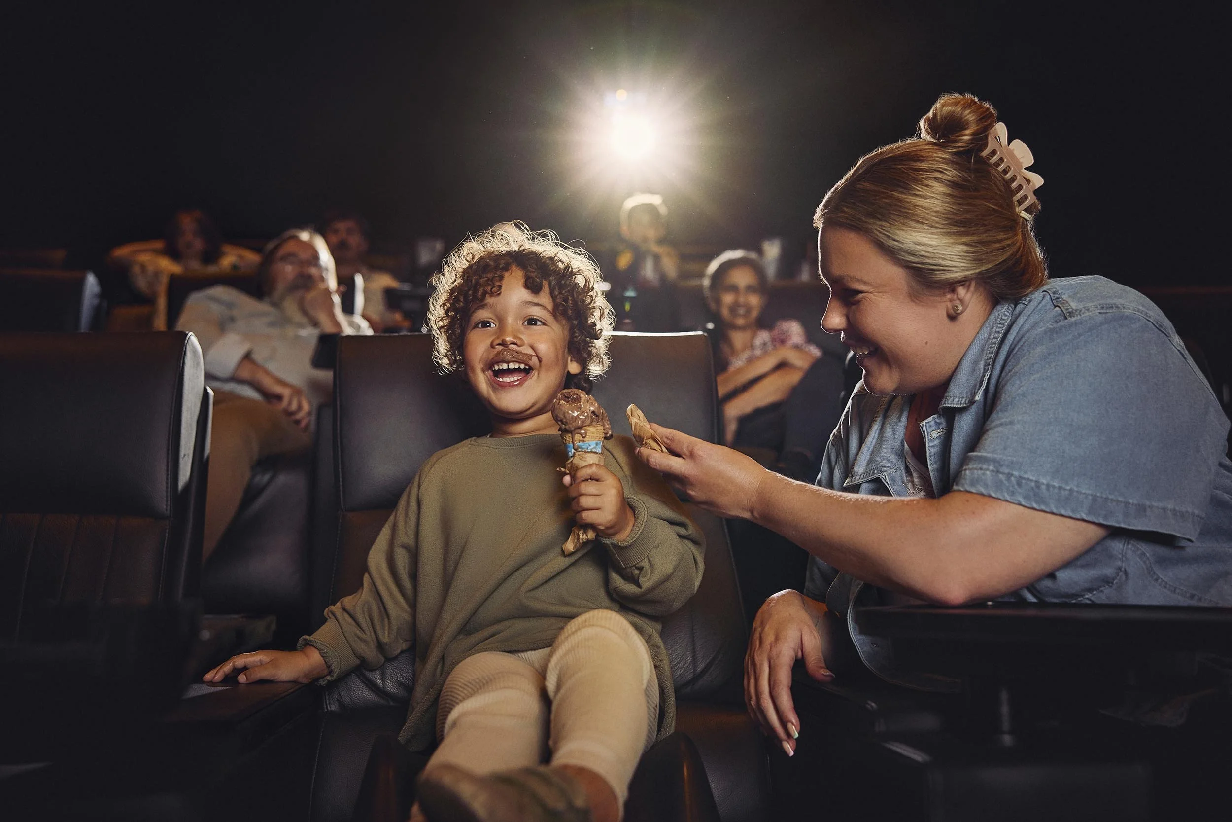A young boy is engrossed in a film whilst eating an ice cream in this lifestyle photography by London based advertising photographer Jon Enoch for leading cinema chain Vue