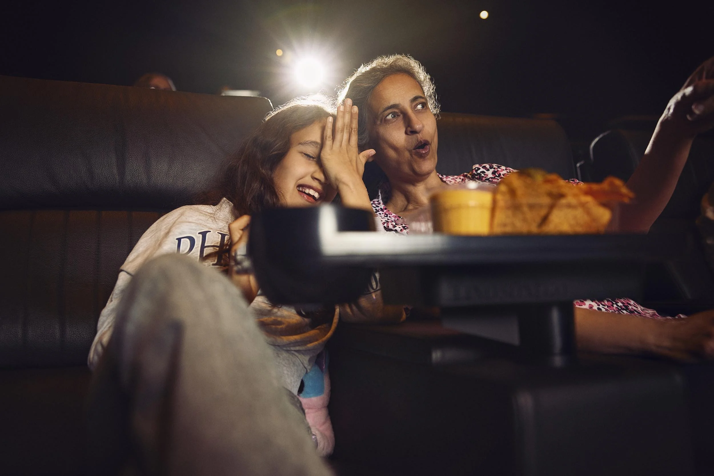 A mother and daughter laugh whilst enjoying a film in this lifestyle photography by London based advertising photographer Jon Enoch for leading cinema chain Vue