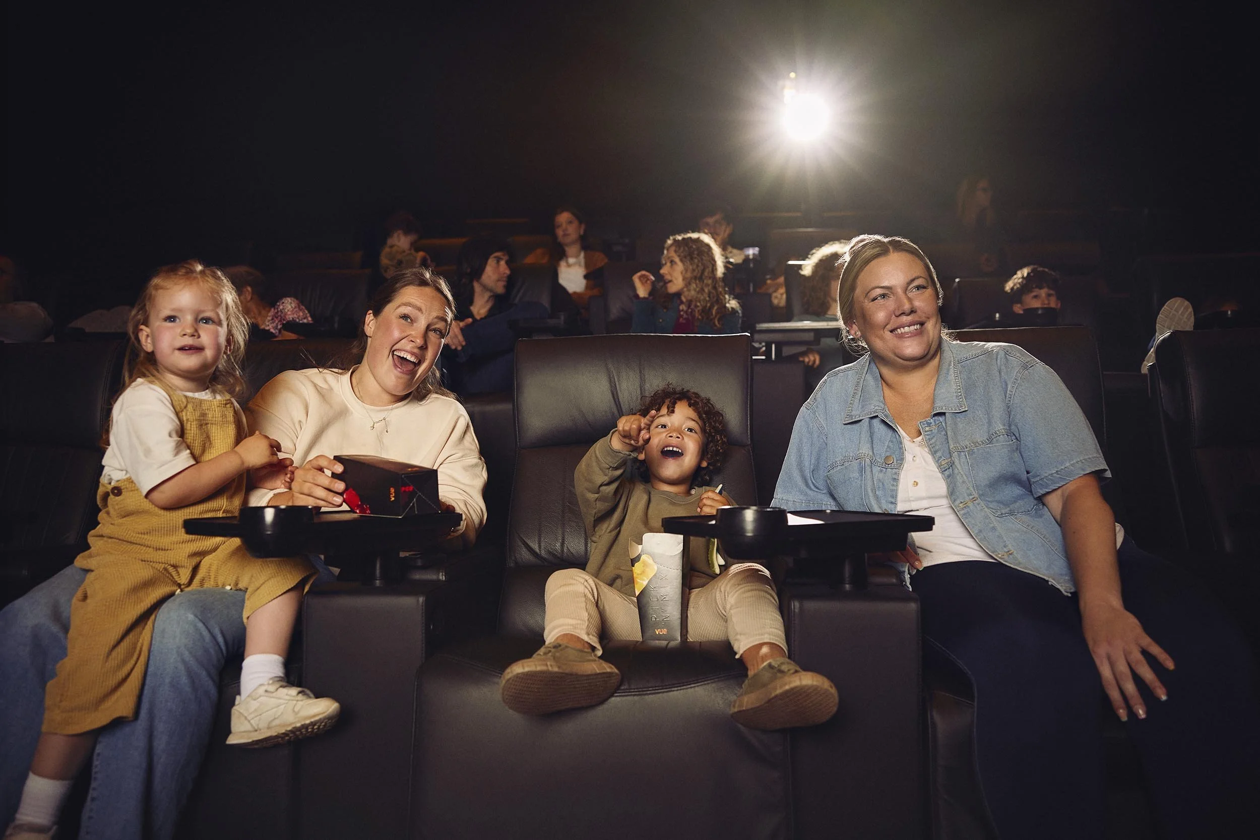 friends and their children enjoy a film at the cinema in this lifestyle image by photographer Jon Enoch
