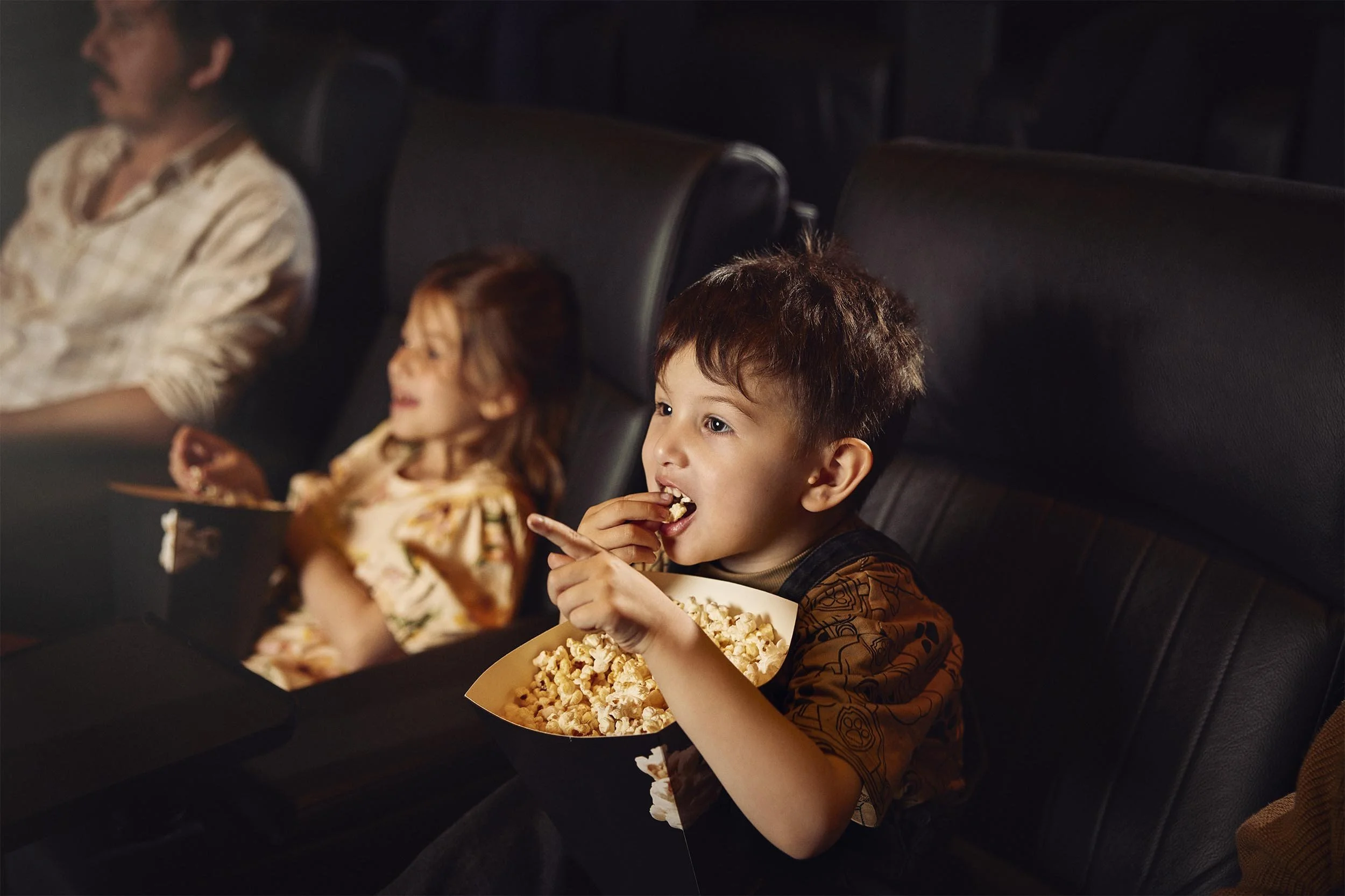 A broth and sister and engrossed in a film at a cinema in this lifestyle photography by Jon Enoch