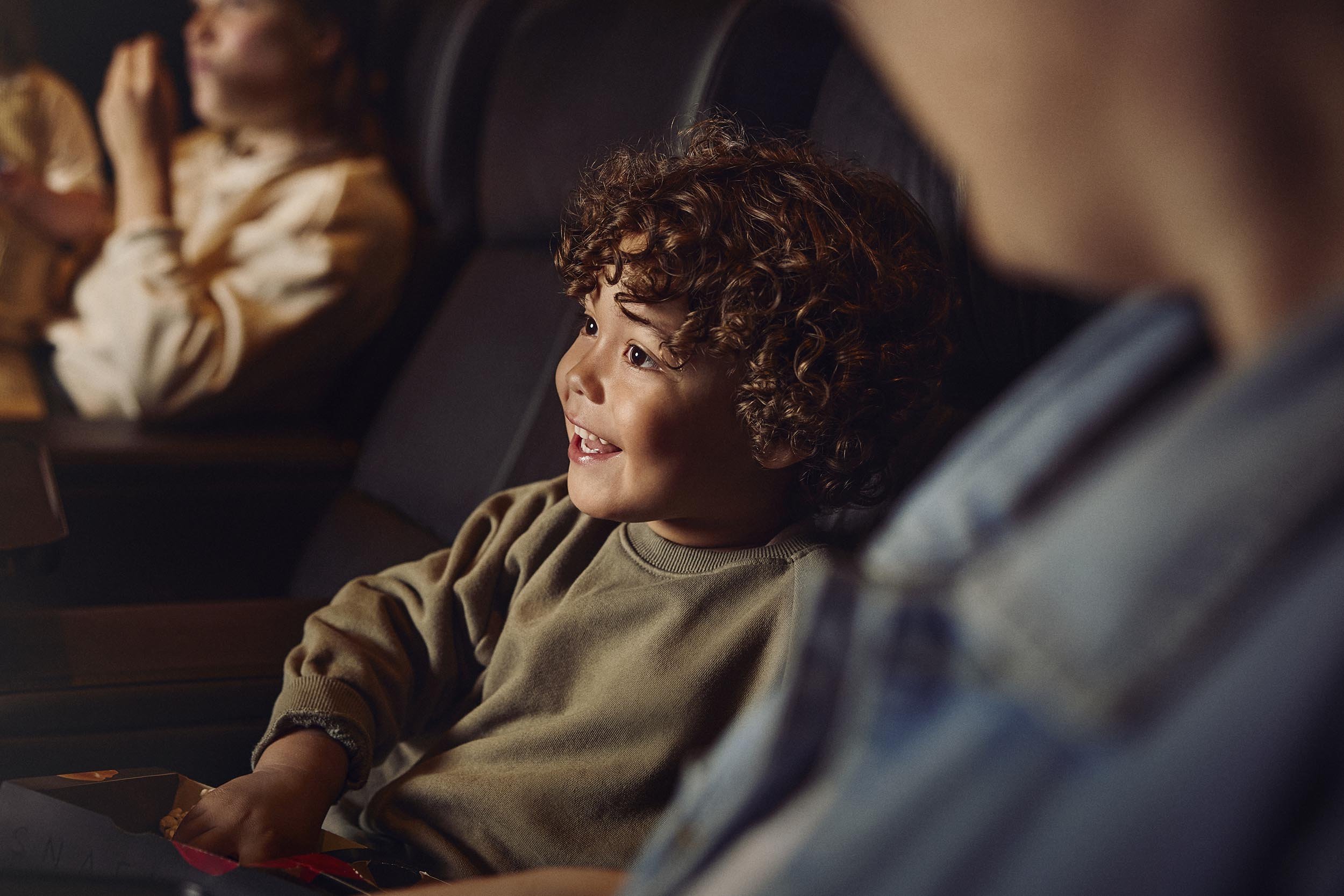 A child sits watching a film in the cinema in this lifestyle photography by london based advertising photographer Jon Enoch
