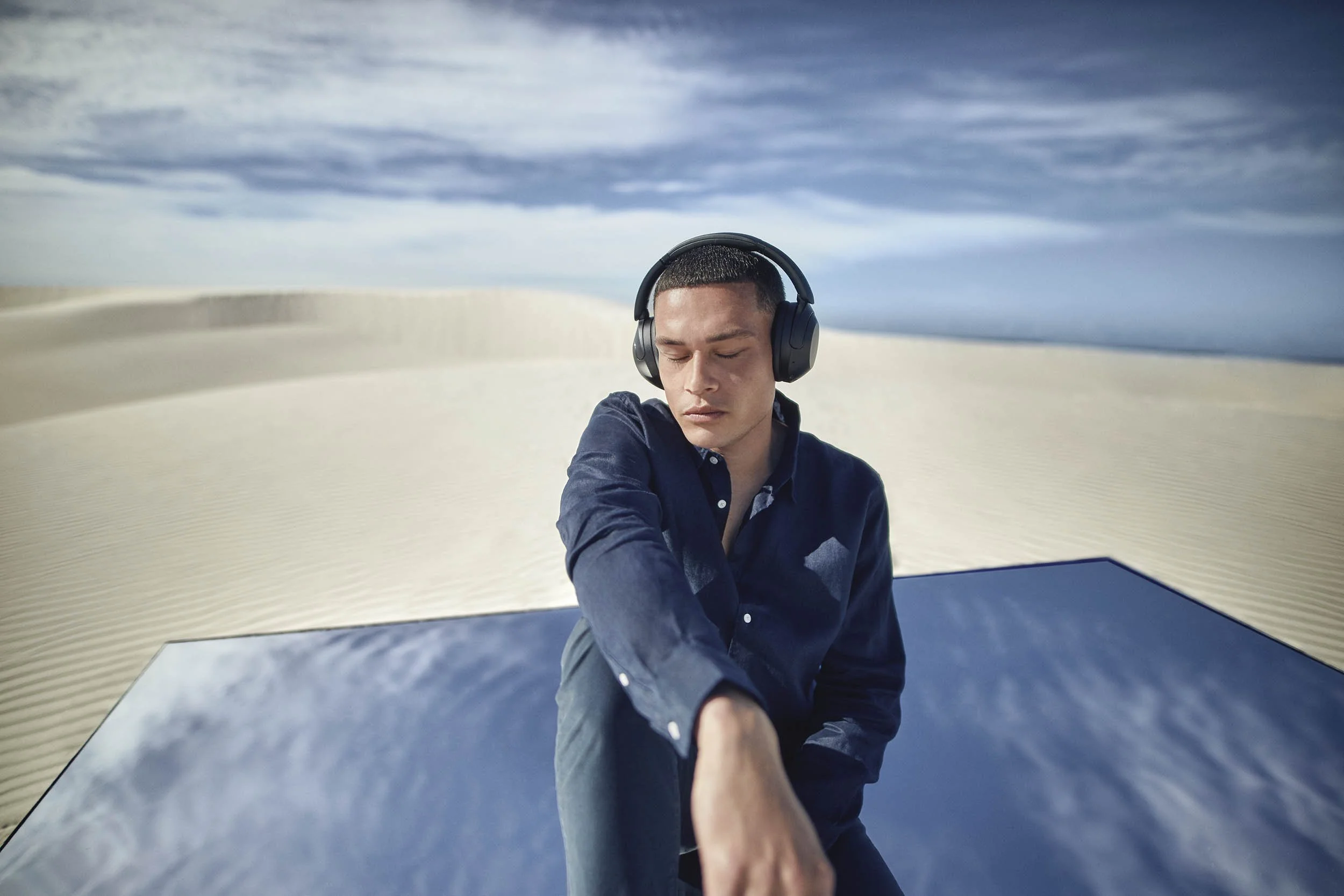 A young man has his eyes closed whilst he listens to music on headphones in this technology lifestyle image by London based photographer Jon Enoch