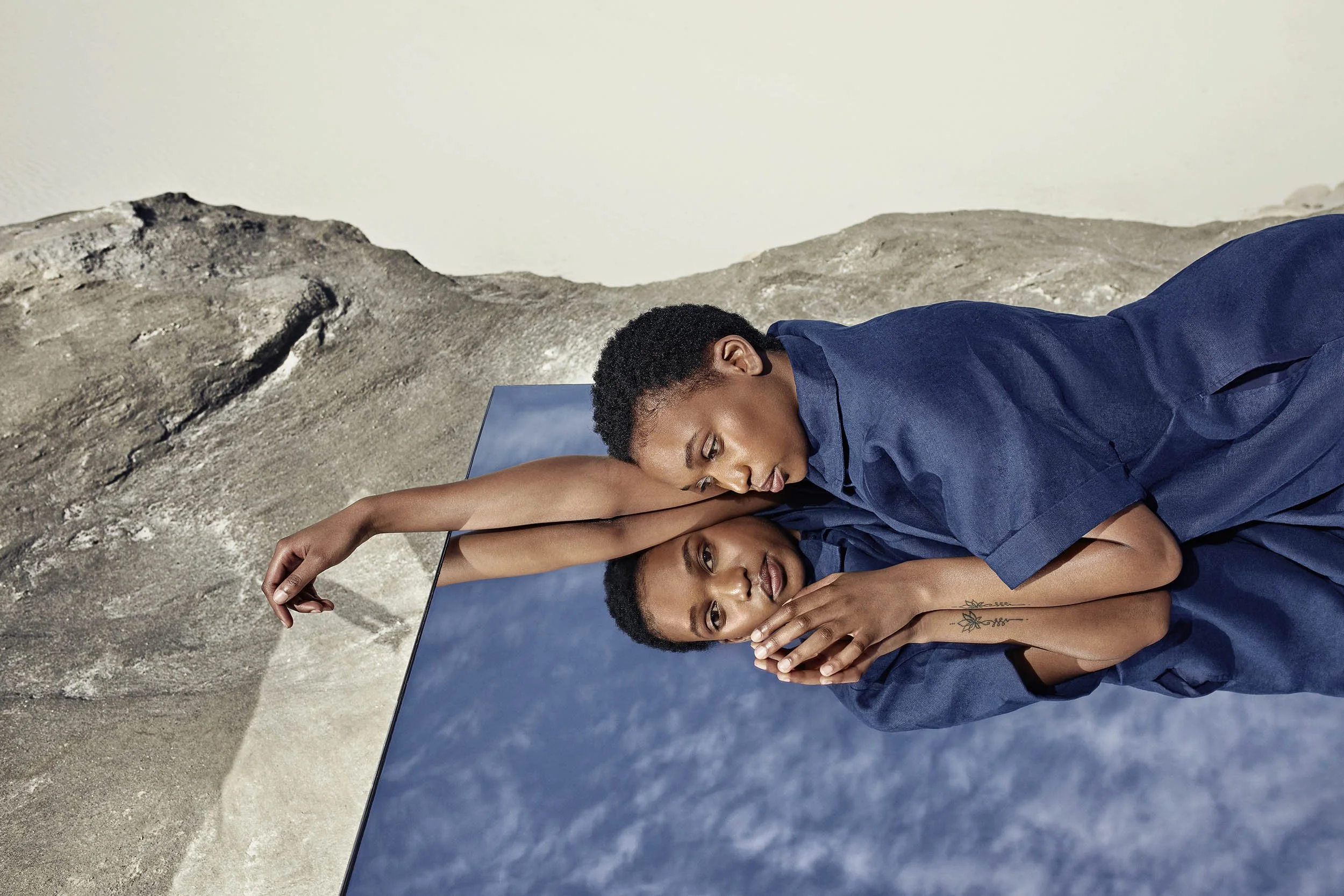 A women looks at camera in the reflection of a mirror in the desert in this lifestyle image by london based photographer Jon Enoch