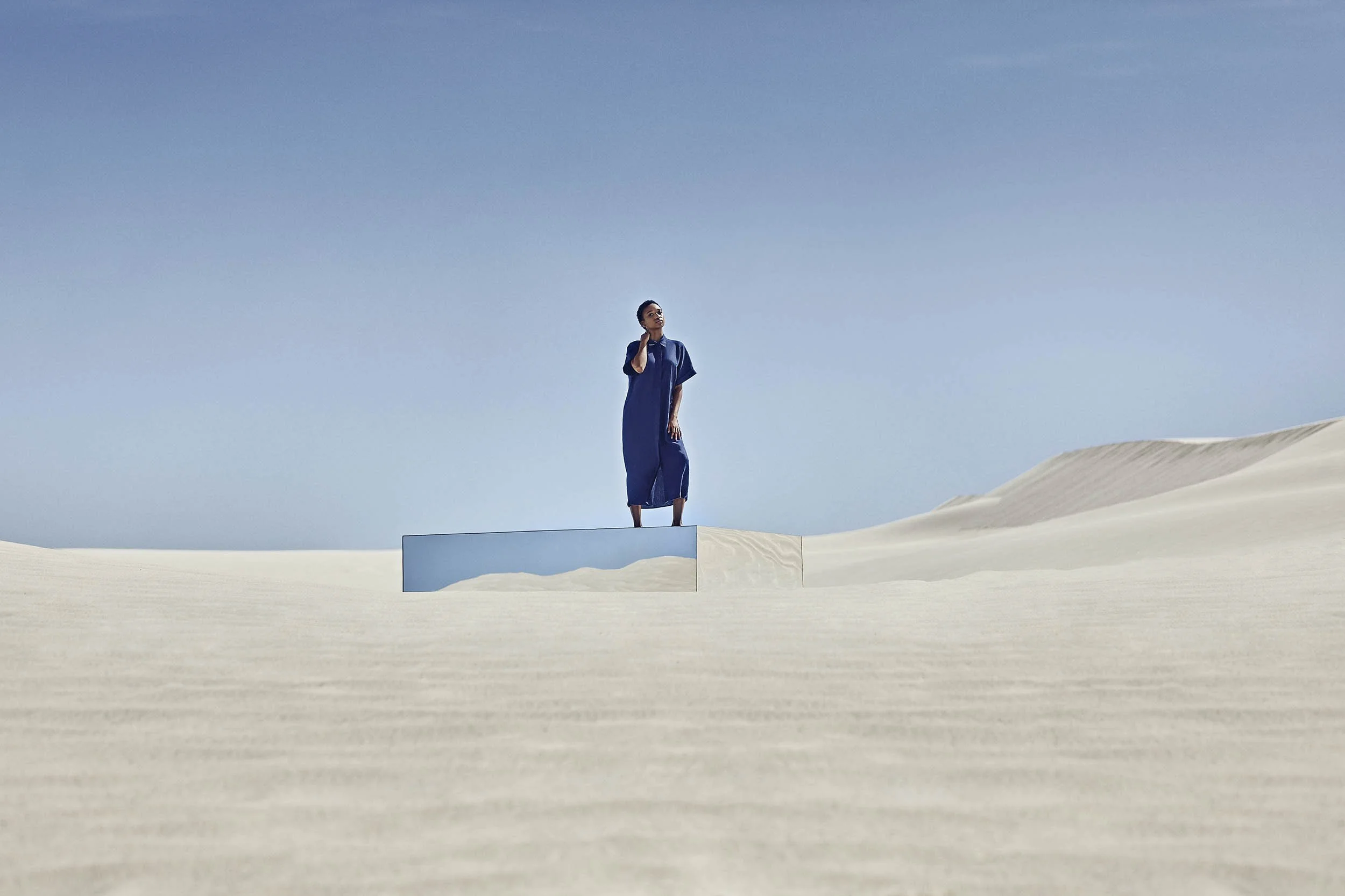 A women stands on top of a mirror the blue sky and sand reflected lifestyle image by Jon Enoch