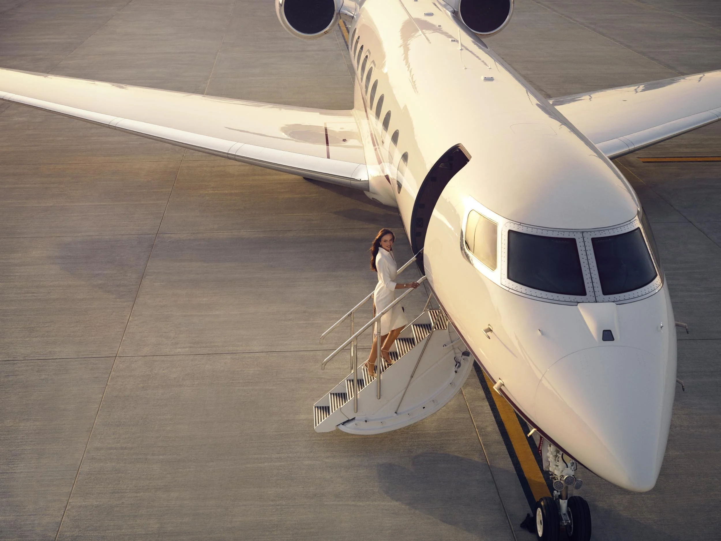 A women boards a private jet as the sun sets in this lifestyle image by photographer Jon Enoch