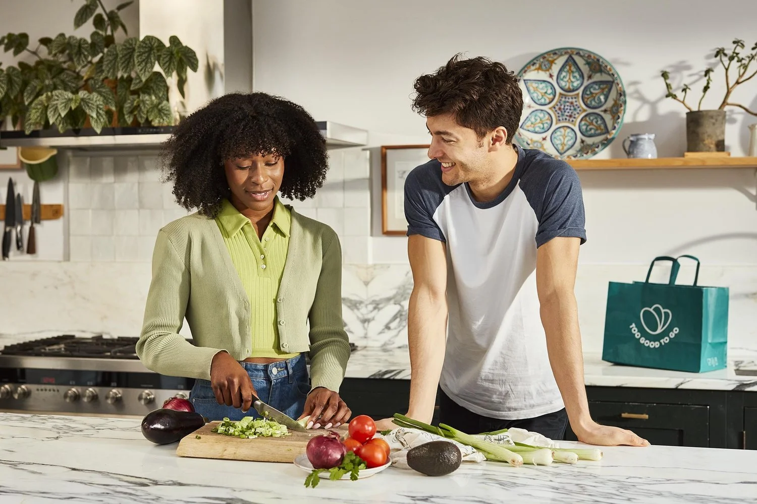 A young couple chat whilst preparing a healthy looking evening meal in this fresh bright lifestyle image by photographer Jon Enoch