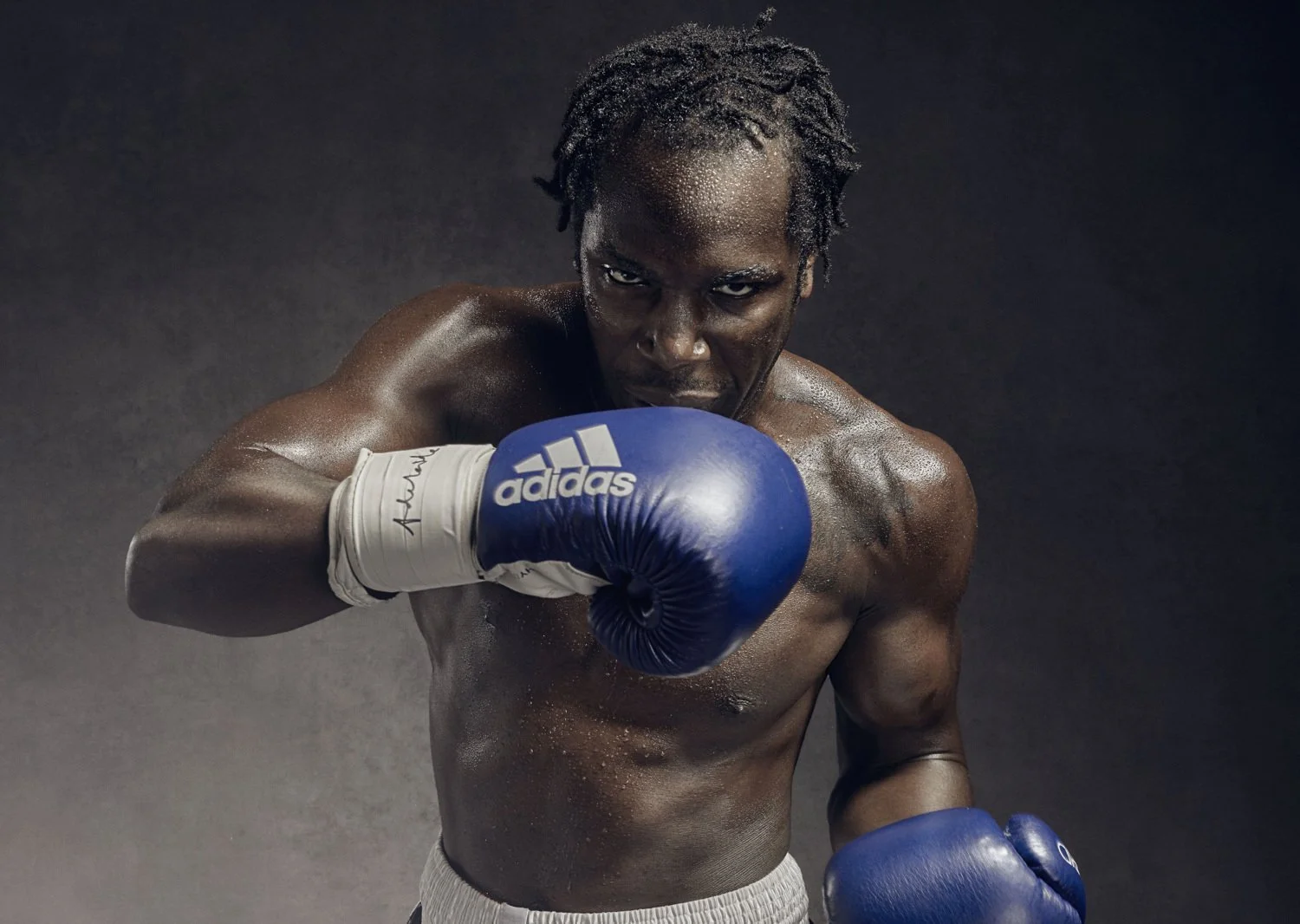 A boxers, gloves raised looks down the camera in this powerful sports portrait by sports photographer Jon Enoch