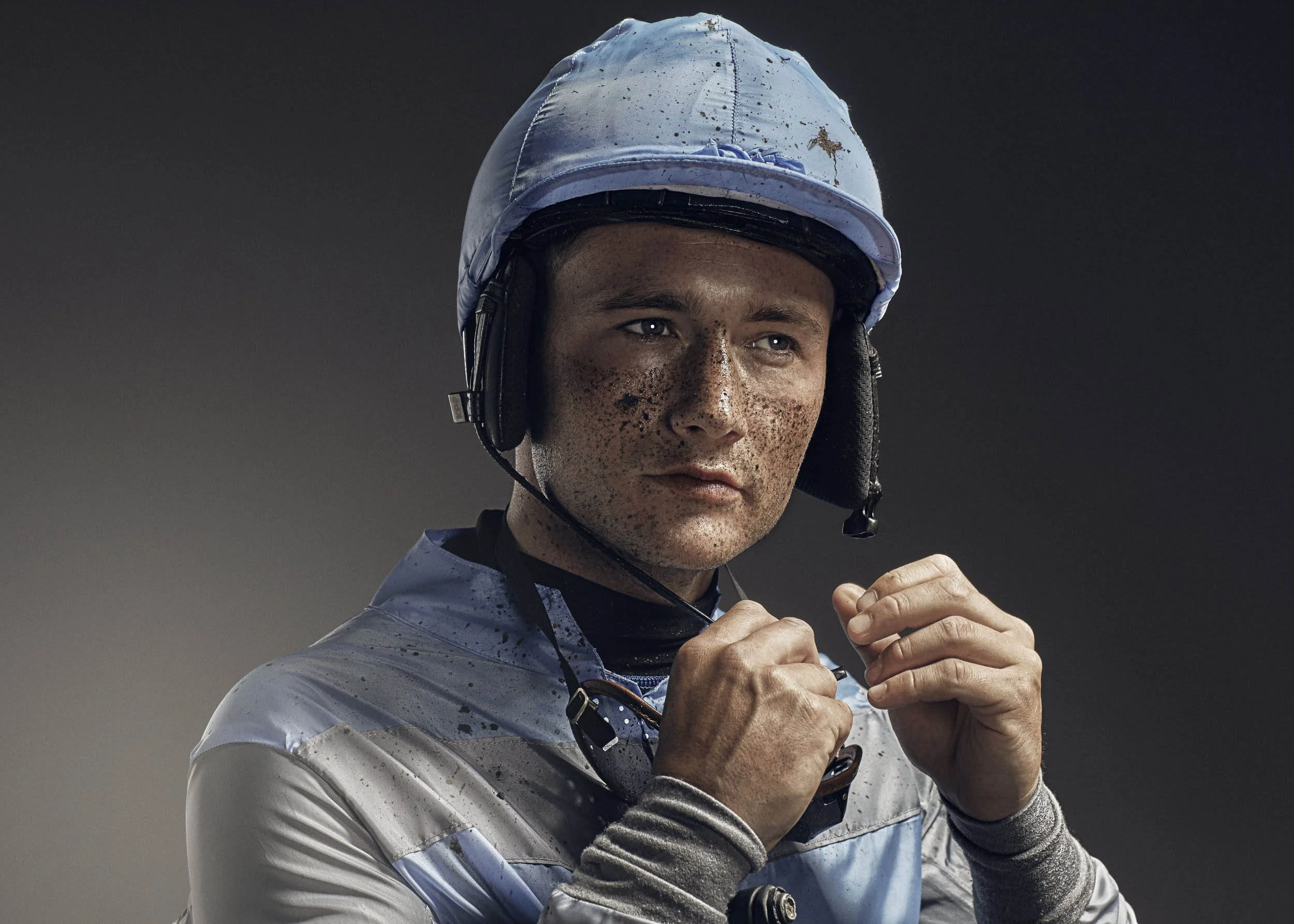 A portrait of a jockey, mud splatters on this face taken my sports photographer Jon Enoch from London
