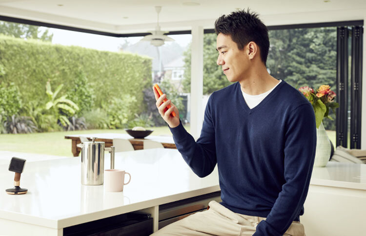 A man uses smart technology in his kitchen in this lifestyle image by Jon Enoch