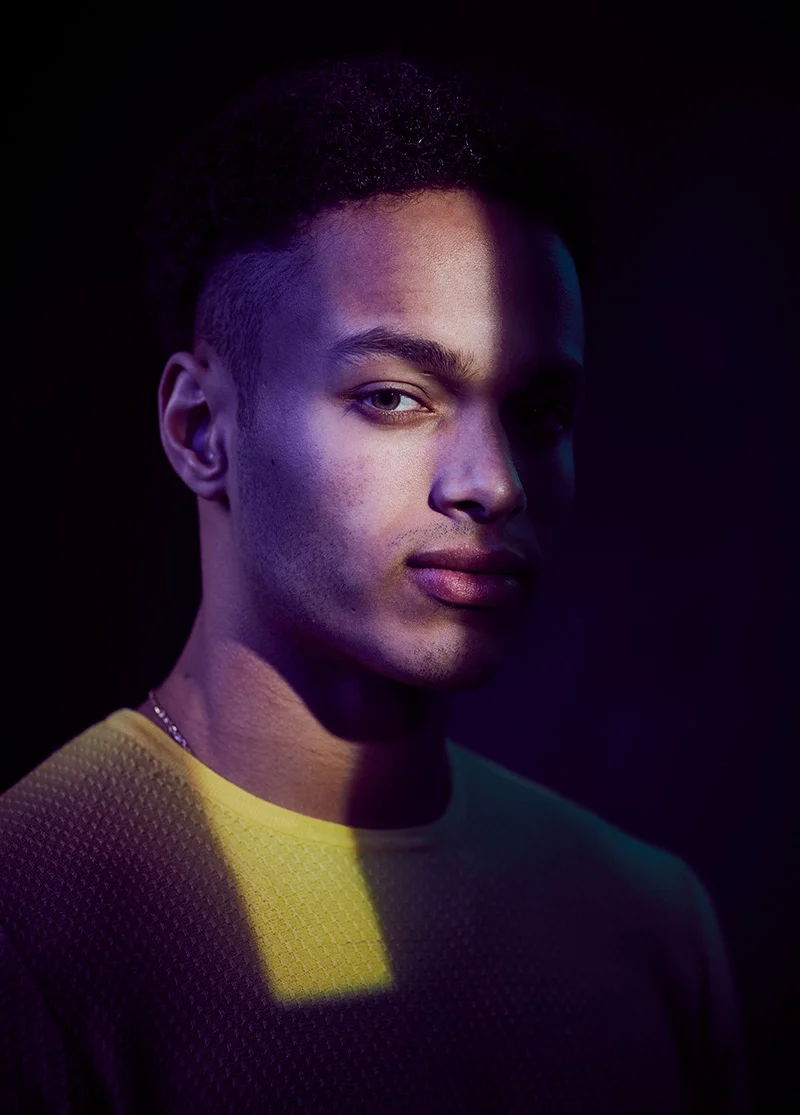 A dark moody yet colourful image of a model in the studio by advertising photographer Jon Enoch