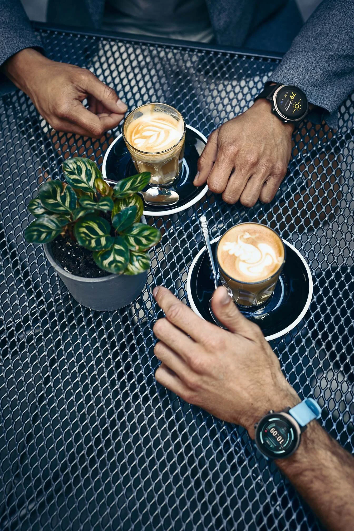 A couple drink coffee whilst using smart watches. Lifestyle photography by Jon Enoch.