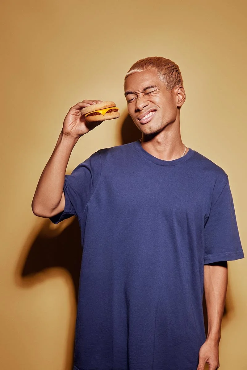A fun vibrant colourful image of a man holding a burger. Food lifestyle photography by Jon Enoch.