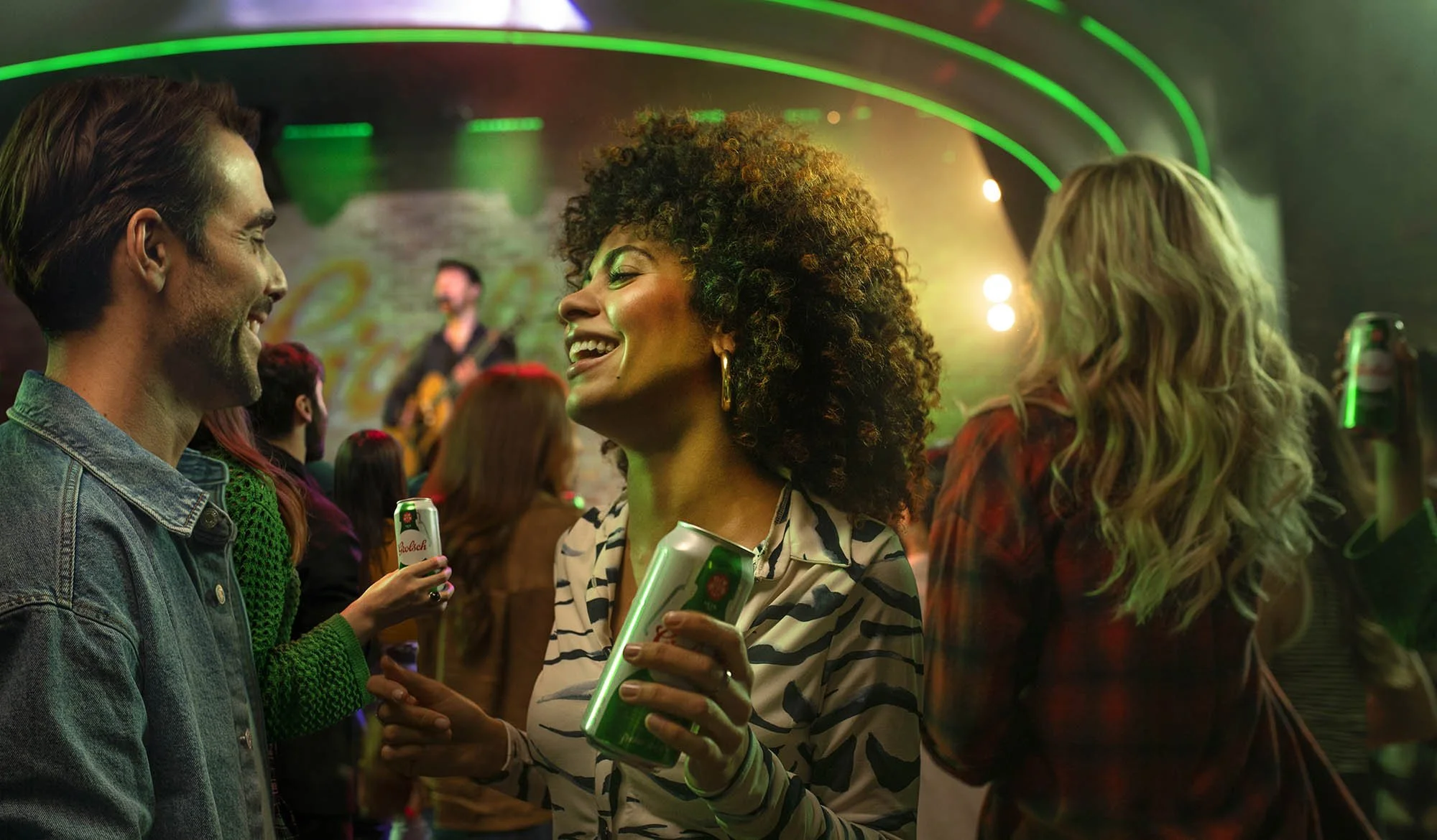 Two friends dance at a music venue whilst enjoying a beer in this lifestyle by photographer Jon Enoch