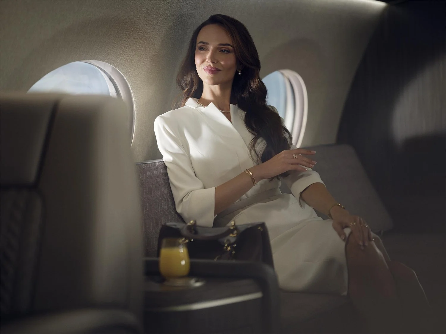 A business traveler sits on her private jet and relaxes as the sun shines through the windows.
