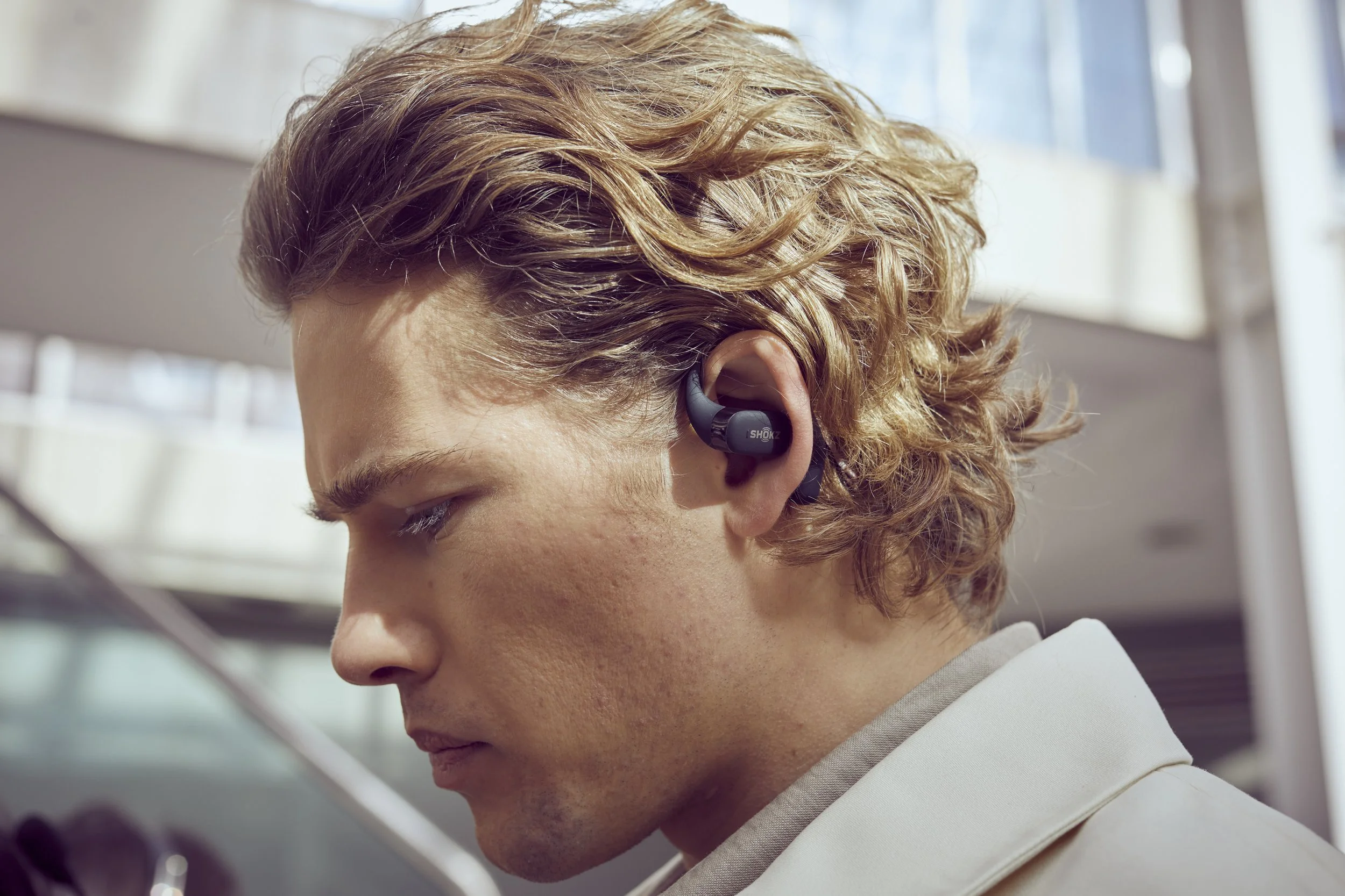 A man walk through a shopping centre deep into a conversation that he is listening to on headphones in this lifestyle photography by Jon Enoch