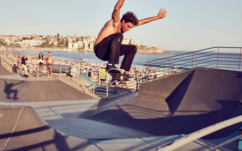 A skateboarder jumps in the air whilst skating at Bondi Beach skate park.