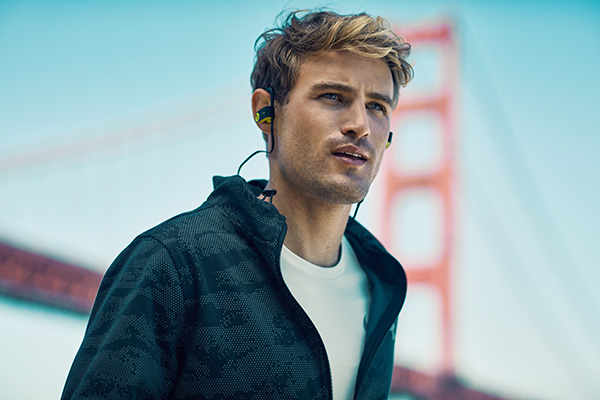 A man wearing beats headphones runs past the San Francisco bridge. Sports lifestyle photographer Jon Enoch.