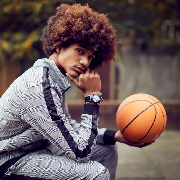 A young man sits and holds a basket ball in this lifestyle image from photographer Jon Enoch