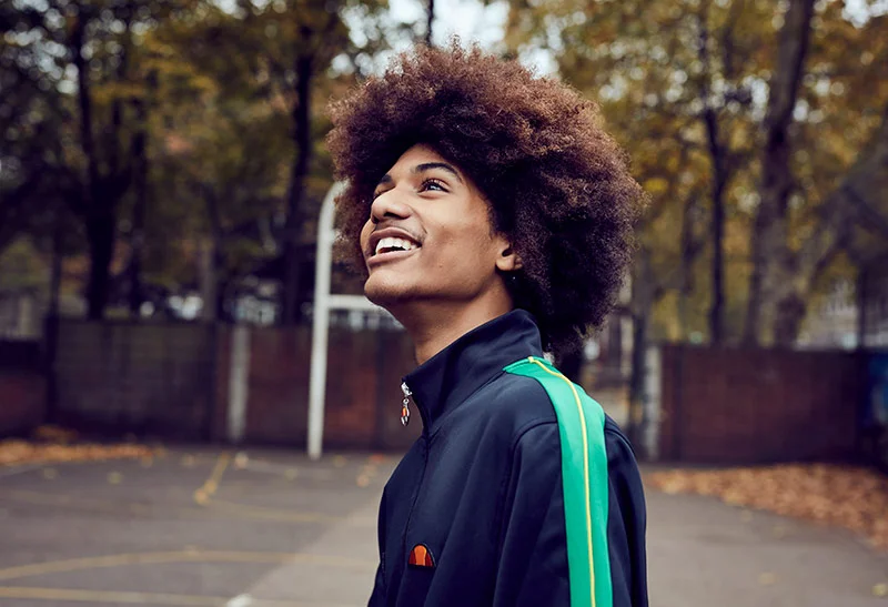 A man on a basket ball court smiles. Lifestyle images by photographer Jon Enoch
