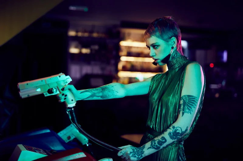A stylist young women plays on a shooting game in a retro gaming arcade. Image taken by photographer Jon Enoch.