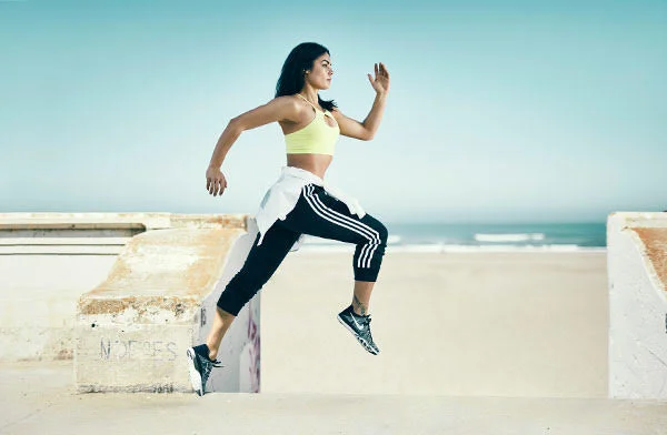 A women runs along the beach front in San Francisco wearing sports clothing. Jon Enoch advertising Photogrpaher.