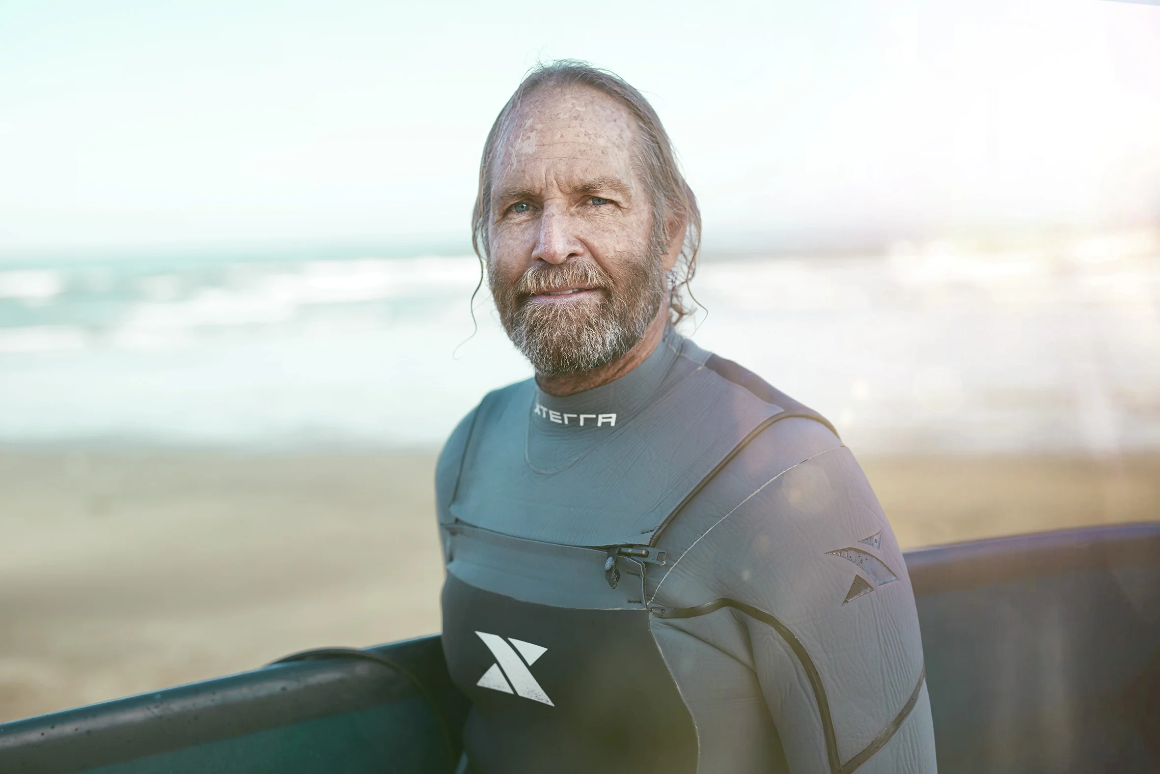 A man poses for a portrait in his wetsuit after going surfing on Pacifica beach. Lifestyle Photographer Jon Enoch.