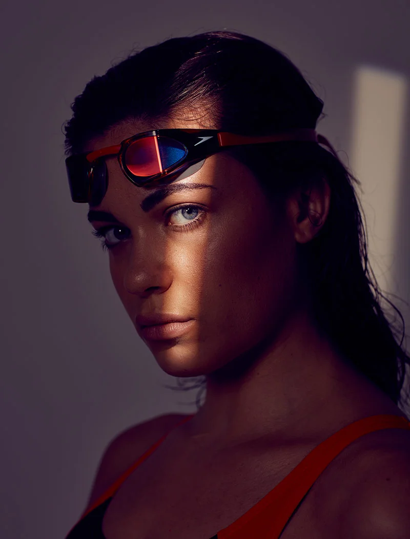 A swimmer with goggles on her head is photographed in a shaft of light by sport photographer Jon Enoch.