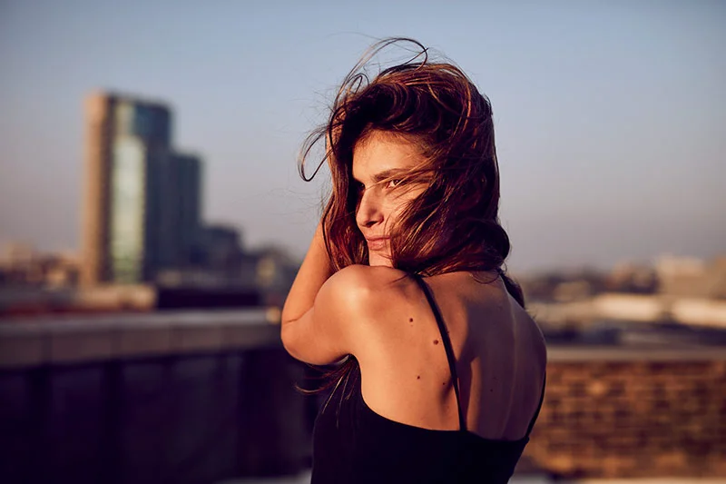 A women enjoys the sun set from a rooftop in Shoreditch taken by lifestyle photographer Jon Enoch