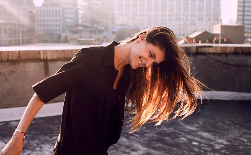 A young women laughs and enjoys herself on a rooftop in central London - lifestyle photography by lifestyle photographer Jon Enoch
