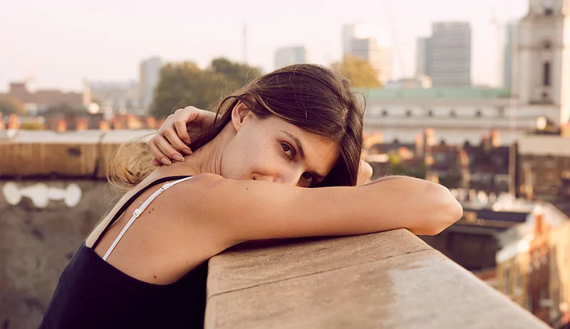 A women smiles as she looks to across the roof tops of central London. Image taken by Jon Enoch