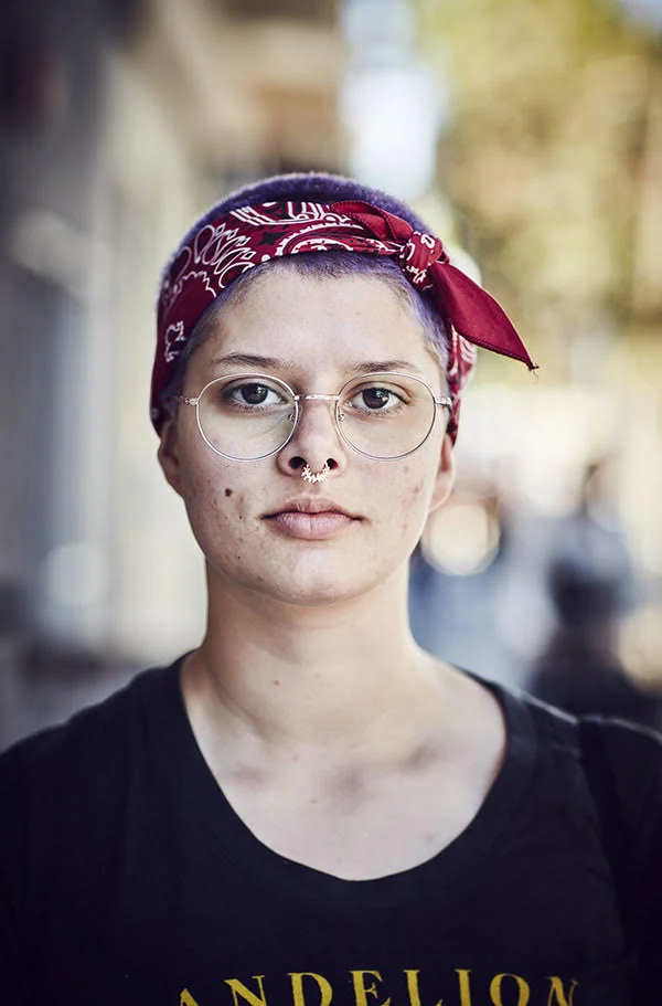 A women with glasses a nose ring and head scarf poses in the street. In the Mission, San Francisco. Photography by portrait photographer Jon Enoch.